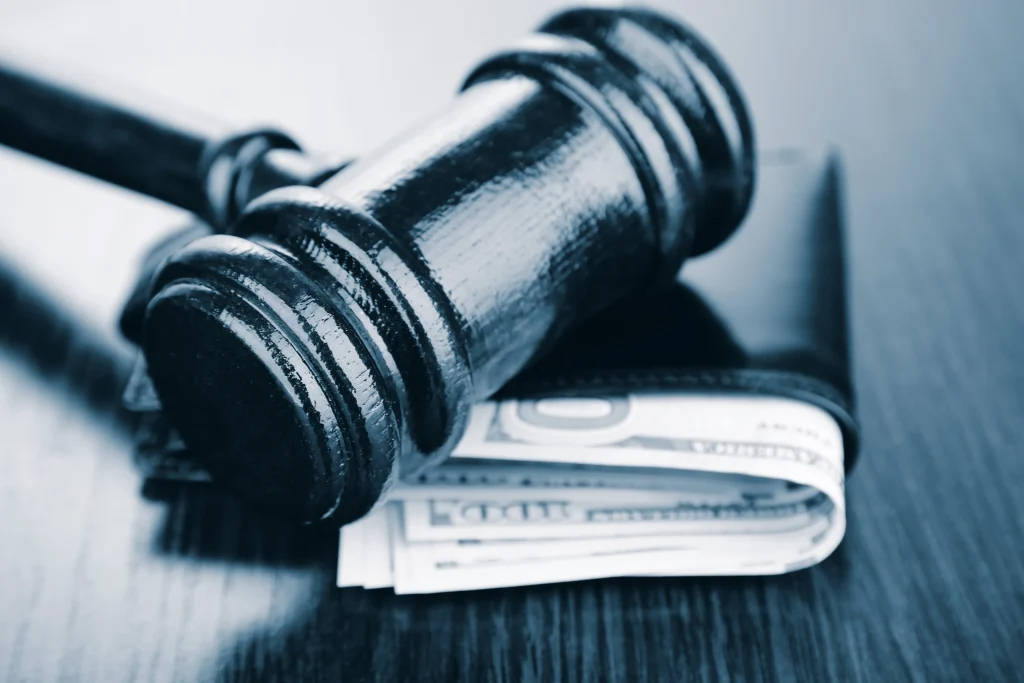Justice gavel sits on a wallet filled with cash. Protect your earnings from collection with a wage garnishment attorney in Texas. Call us now.
