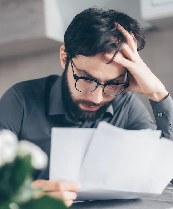 Man in glasses looking at his debt.