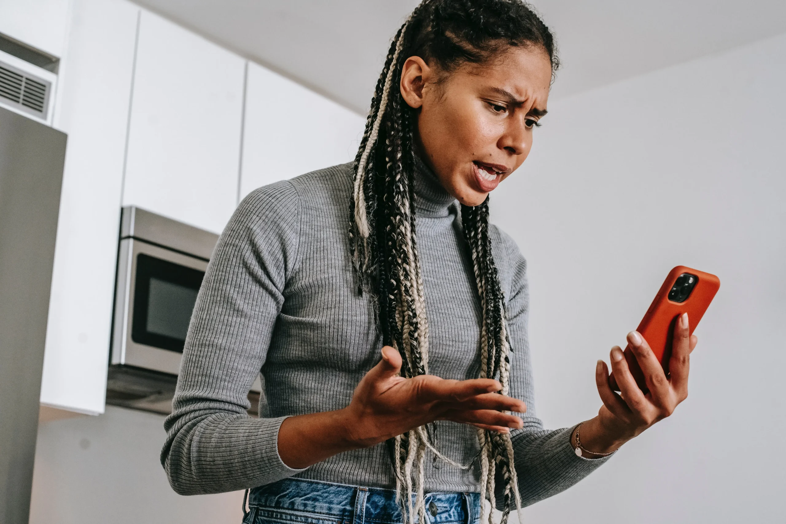 Woman looking at her phone and getting angry because she is being harassed by debt collectors.