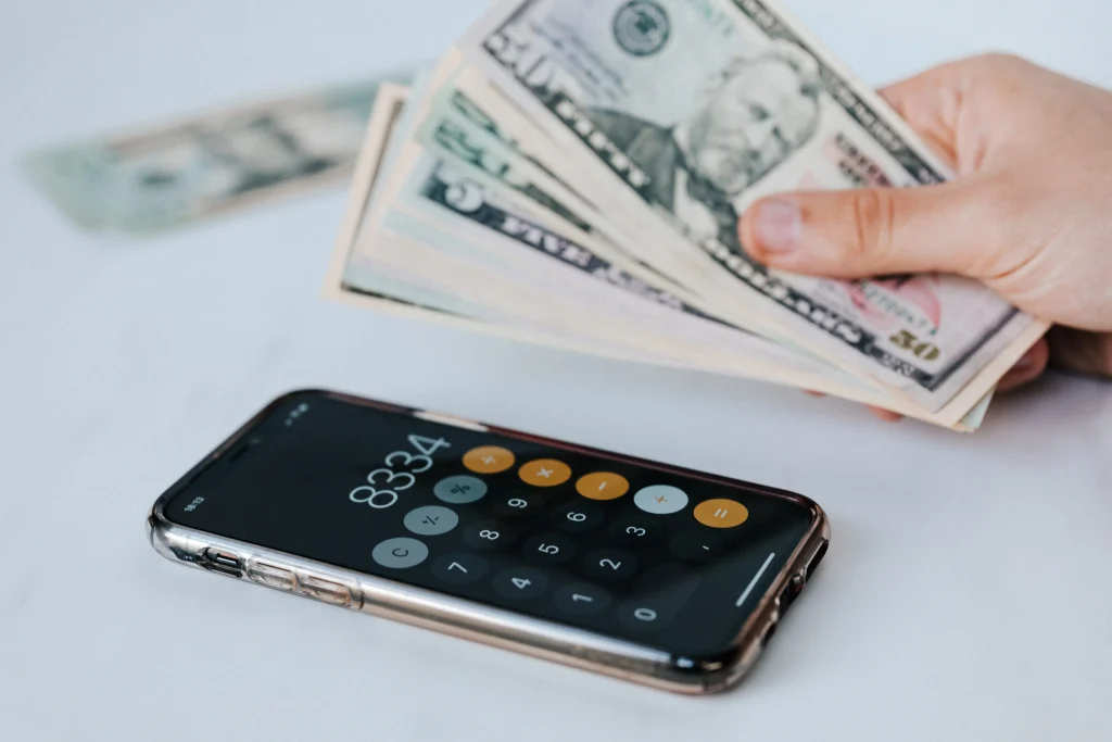 A calculator and a hand holding a stack of bills.