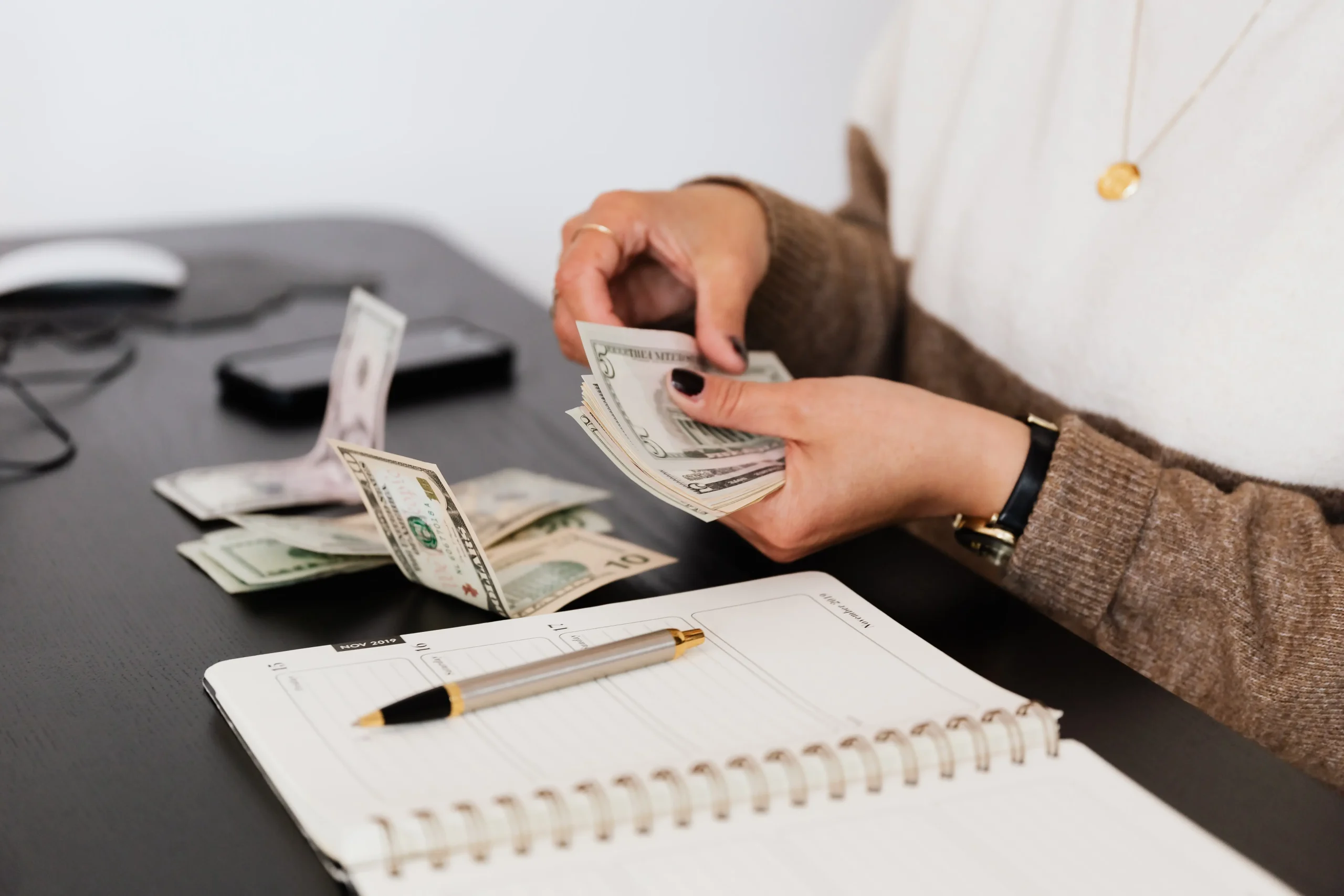 Woman counting a pile of cash. She is organizing her money so she knows what debt to pay. She needs help from an Austin debt collections lawyer