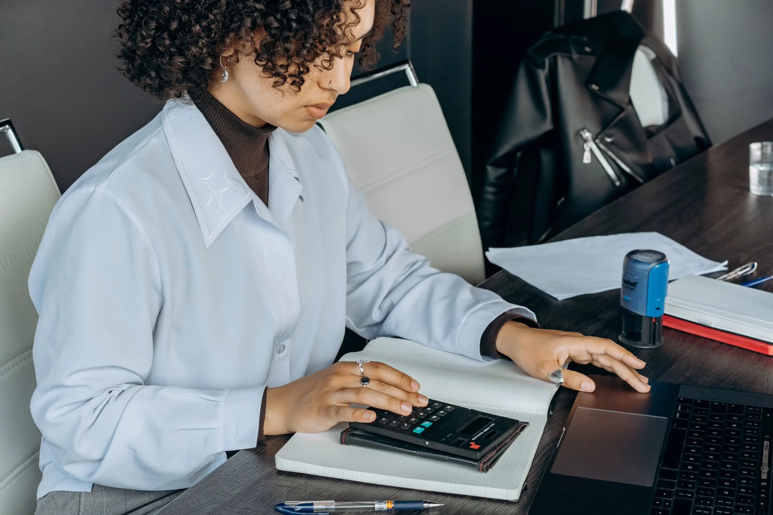 Someone working on her laptop and a calculator.