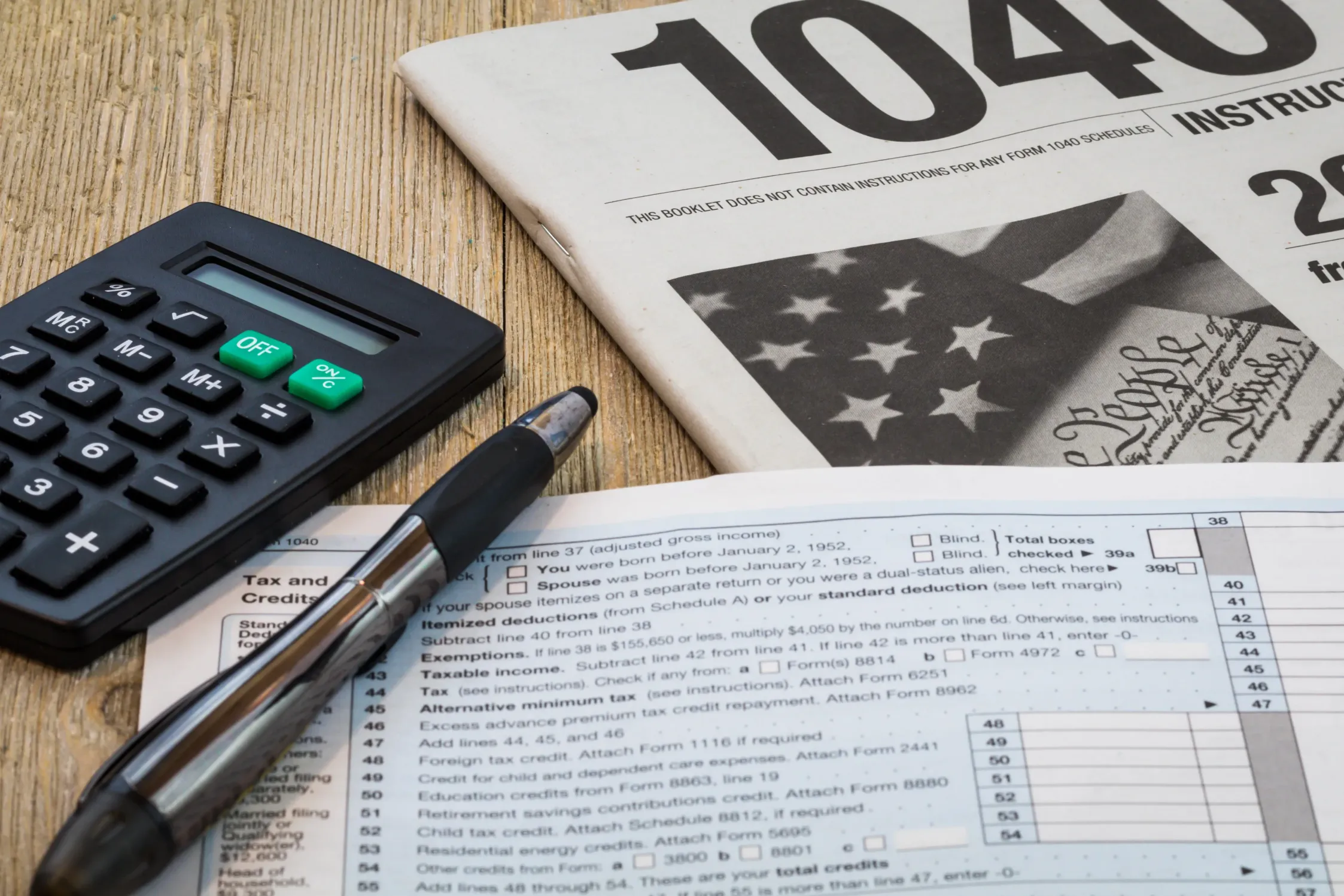 Tax forms, calculator and pen on a desk.