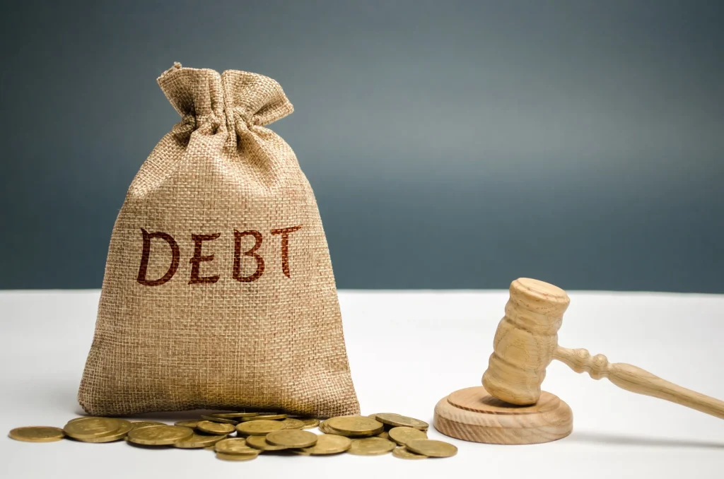 A bag with debt written on it next to a gavel.