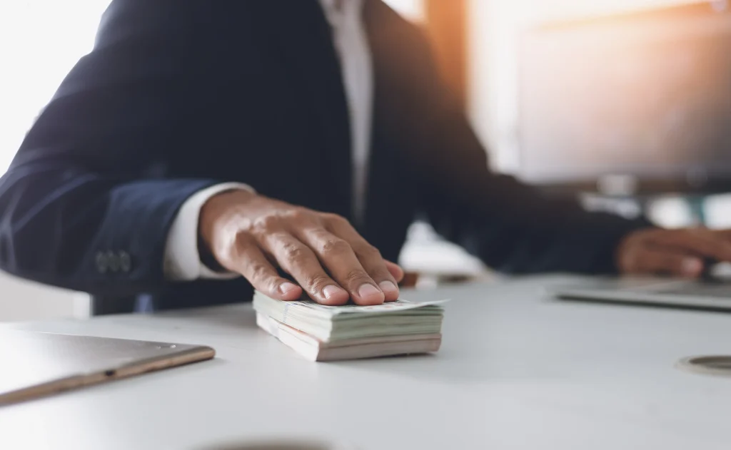 A business man sliding a stack of bills.