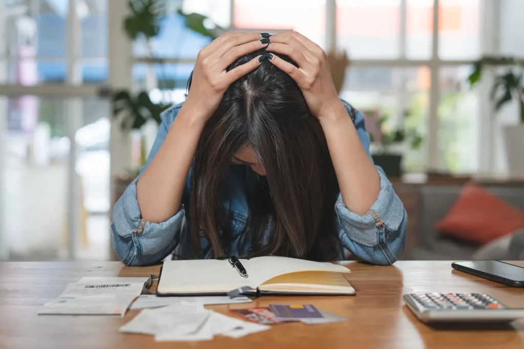 A woman holding her head looking at paperwork.