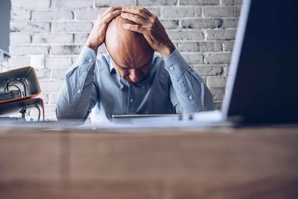 A man holding his head looking at paperwork.