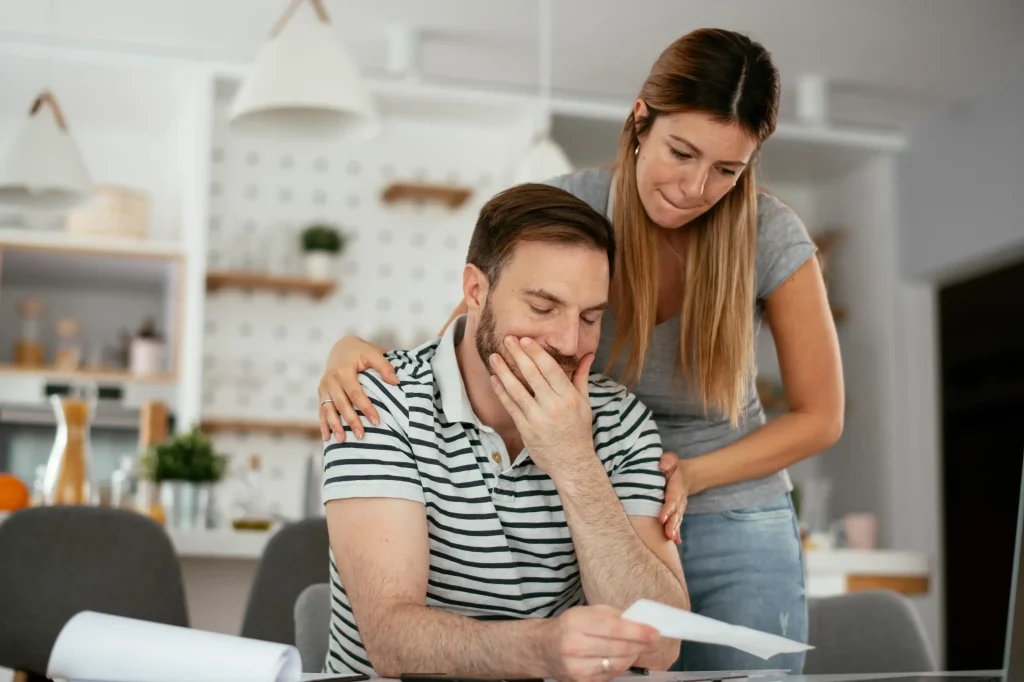 A couple looking worried reviewing tax documents.