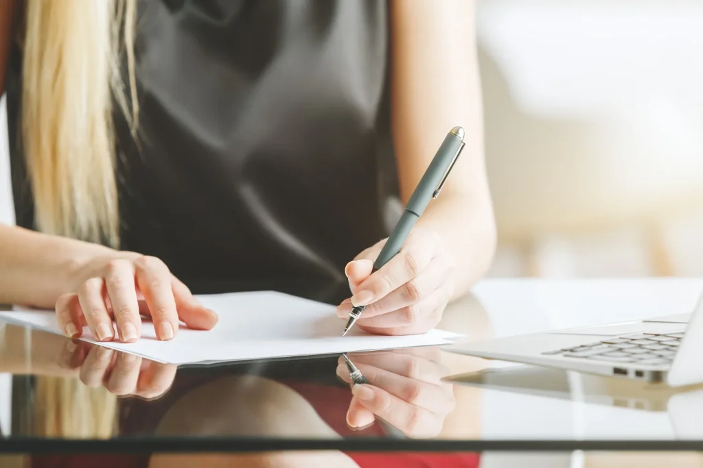 A woman writing on paperwork.
