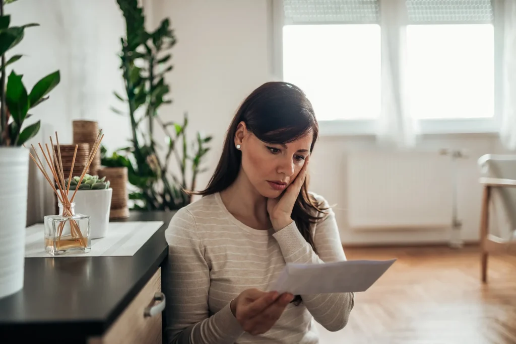 A woman looking at paperwork looking worried.